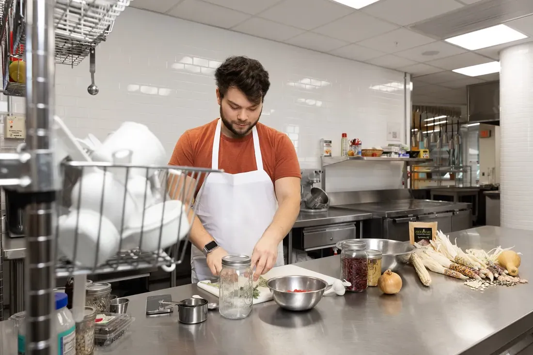 Alumni Ethan Tyo ’17, G’23 cooking in kitchen classroom.